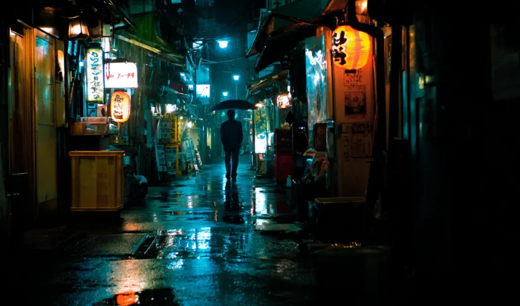 Σκοτεινό στενό στο Τόκιο με μοναχικό άνθρωπο τη νύχτα.