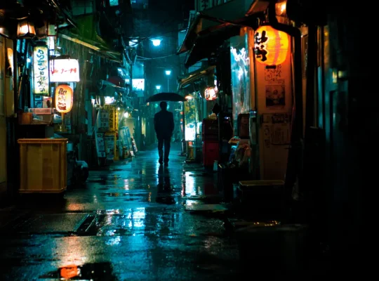 Σκοτεινό στενό στο Τόκιο με μοναχικό άνθρωπο τη νύχτα.