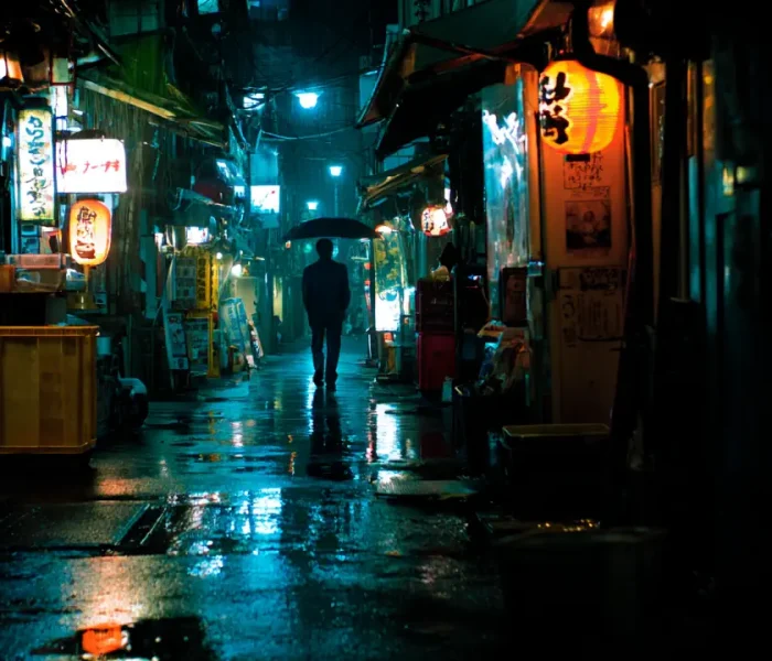 Σκοτεινό στενό στο Τόκιο με μοναχικό άνθρωπο τη νύχτα.