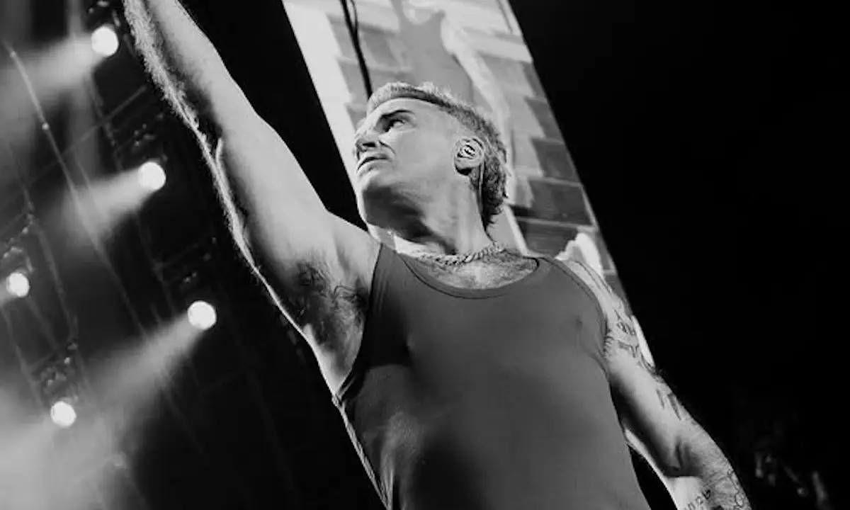 Ο Robbie Williams στη συναυλία του στο Καλλιμάρμαρο, γονατιστός με το χέρι υψωμένο προς το κοινό.